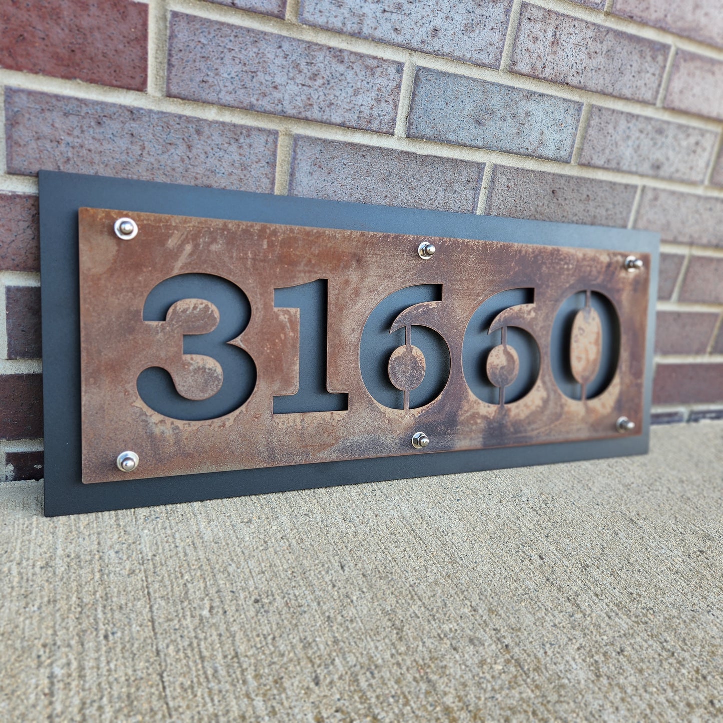 Rust over black layered metal house address sign