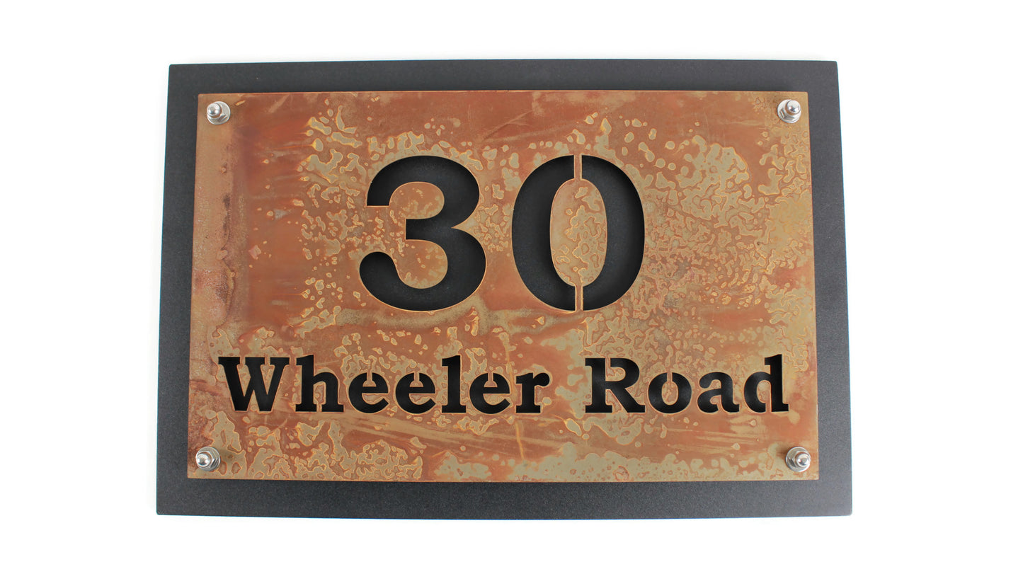 Rust over black layered metal house address sign