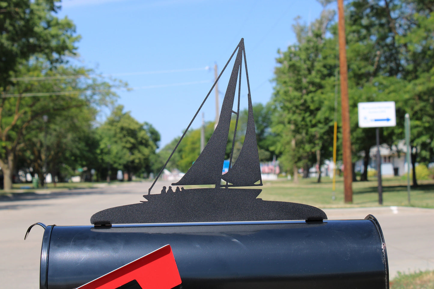 Black sailboat mailbox topper installed on a mailbox