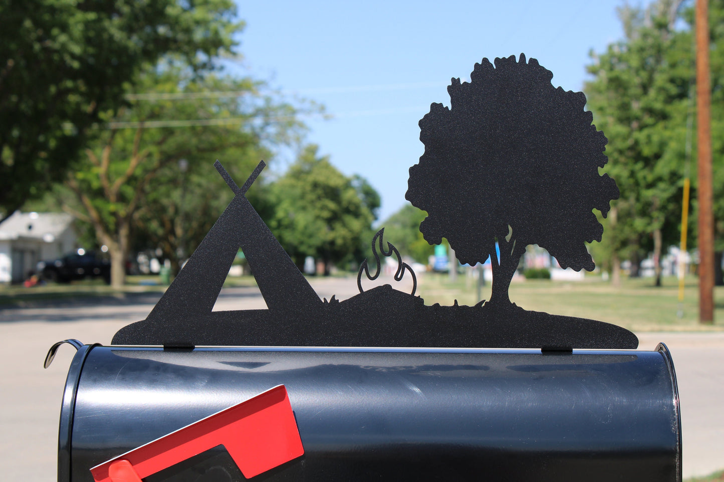 Black tent, tree, and campfire mailbox topper installed on a mailbox