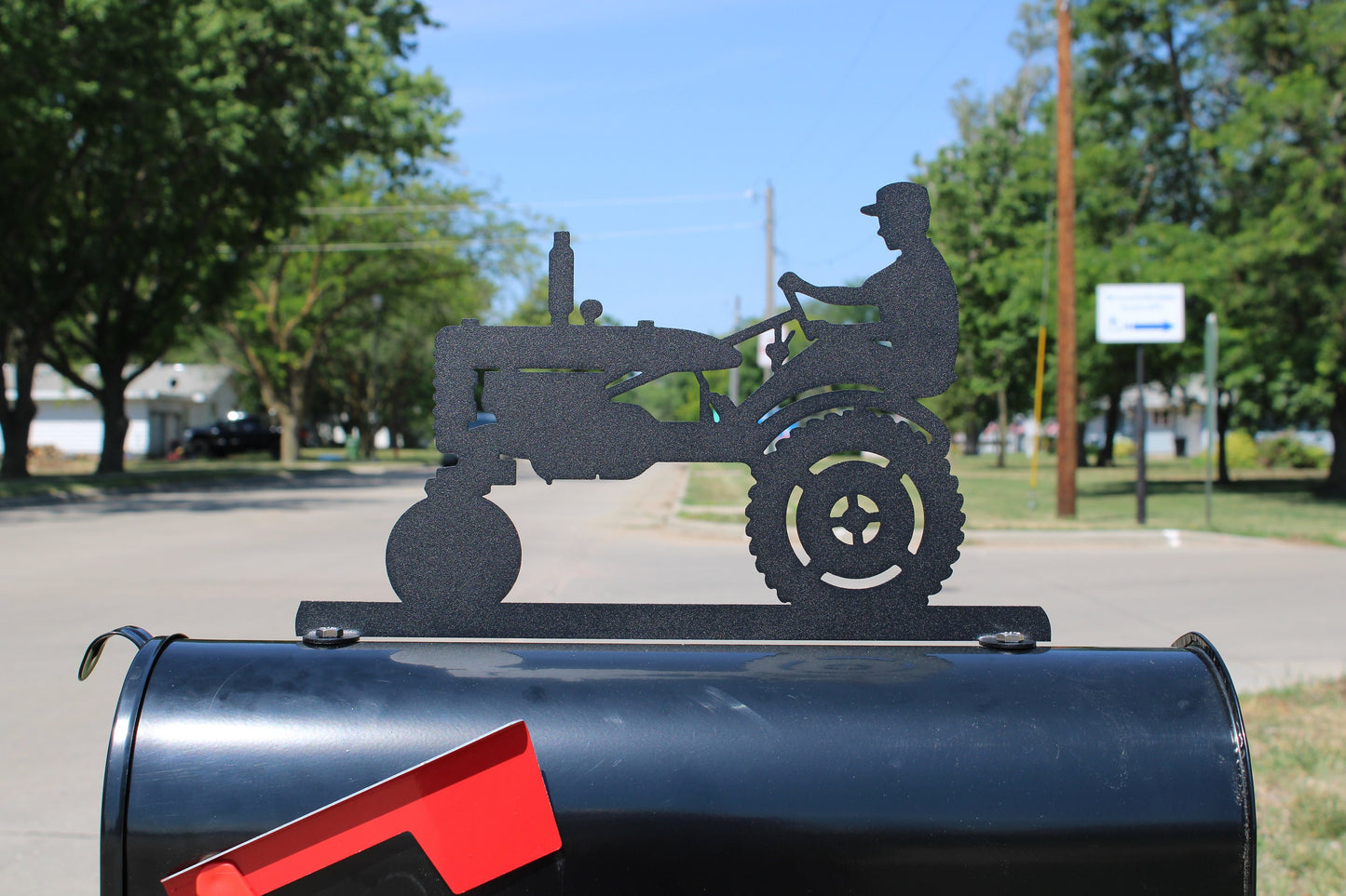 Black vintage tractor and driver mailbox topper installed on a mailbox