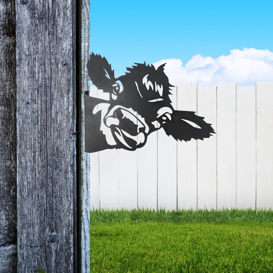 Black powder coat metal cow head peeking around a tree