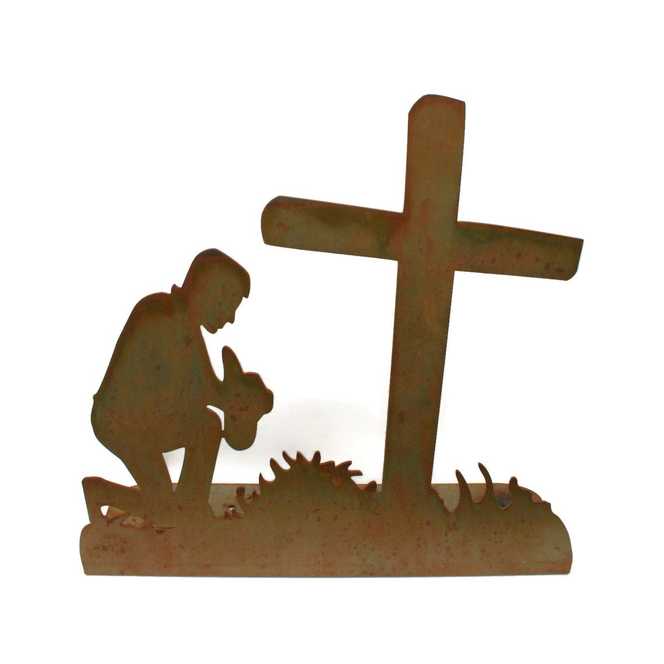 Rusty metal praying cowboy kneeling in front of a cross