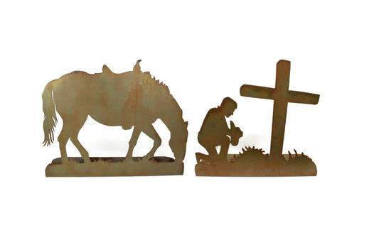 Rusty metal praying cowboy kneeling in front of a cross with a horse