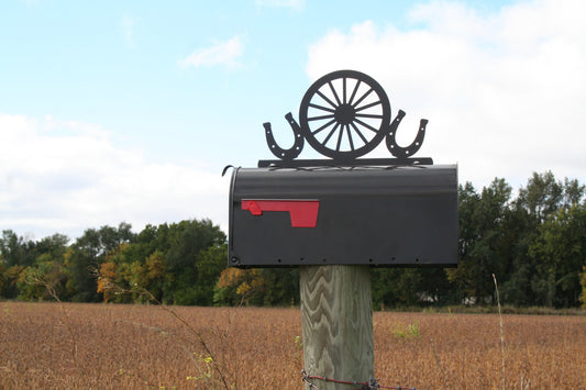 Black horseshoes and wagon wheel mailbox topper installed on a mailbox.