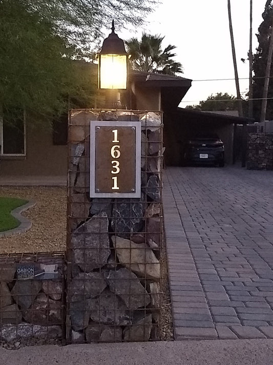 Rust over aluminum vertical layered metal address sign near a driveway