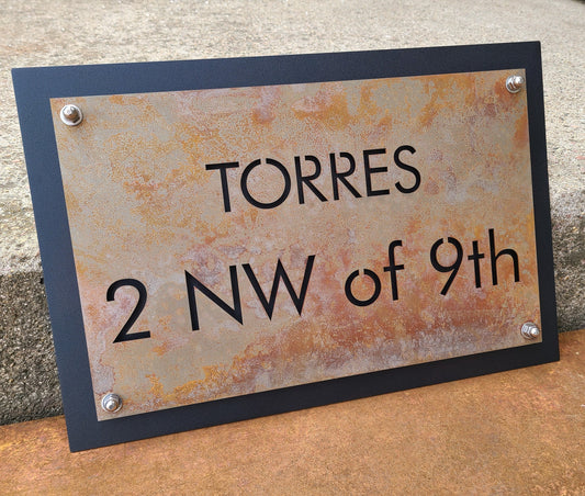 Rust over black layered metal address sign