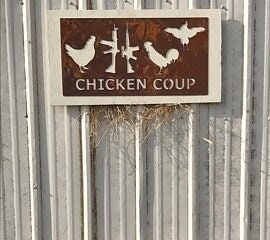 Rusty metal hanging chicken sign with silhouettes of hens, chicks, roosters, and a rifle gun with text saying Chicken Coup