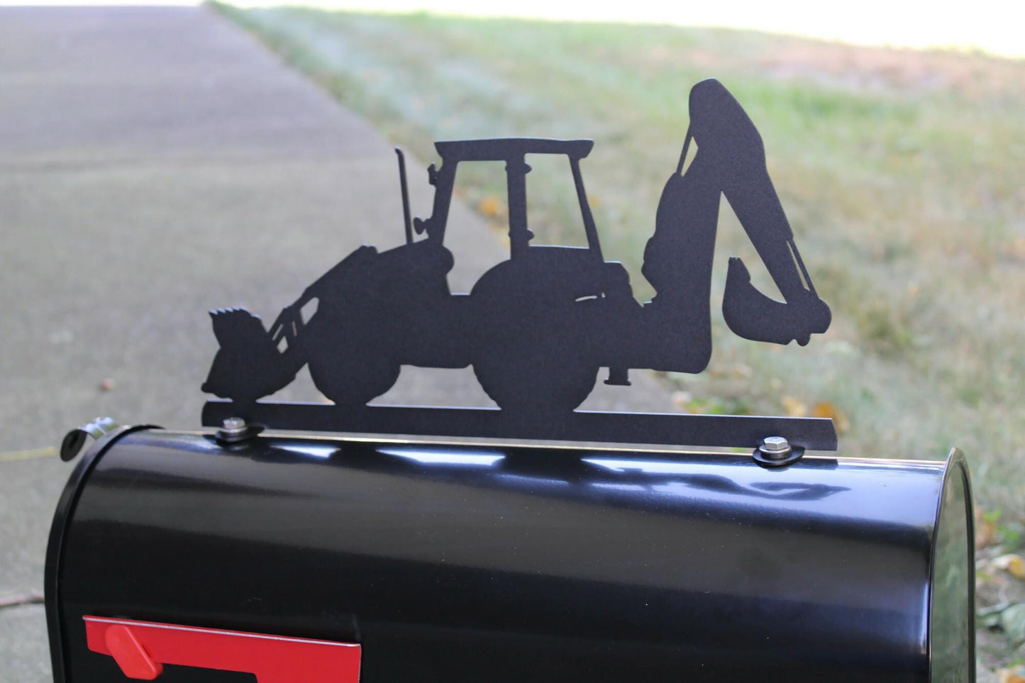Black backhoe mailbox topper installed on a mailbox.