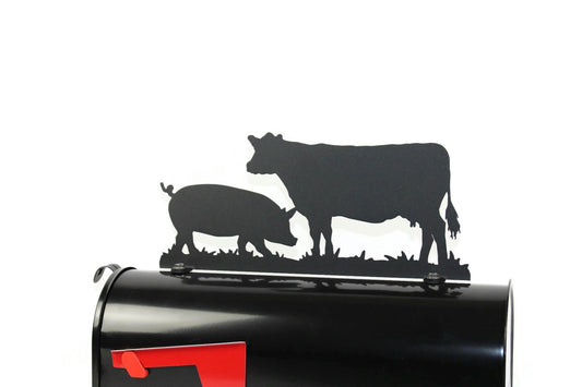 Black cow and pig mailbox topper installed on a mailbox.