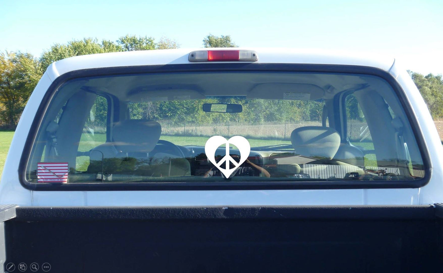 White peace heart vinyl decal on the back window of a pick up