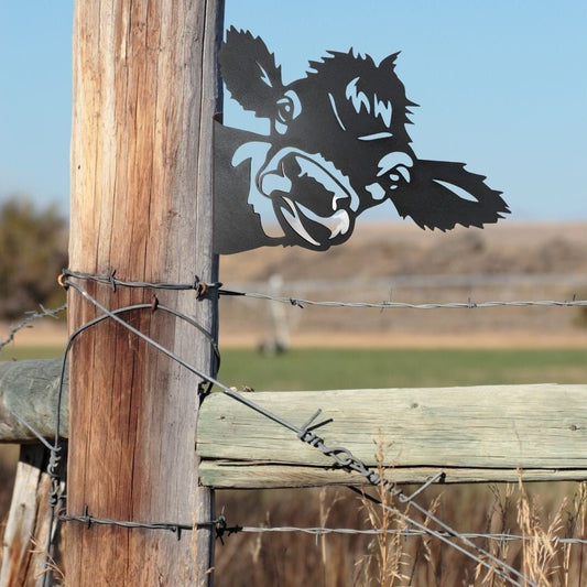 Black powder coat metal cow head peeking around a tree
