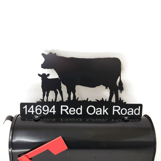 Black cow and calf standing mailbox topper with custom address installed on a mailbox.