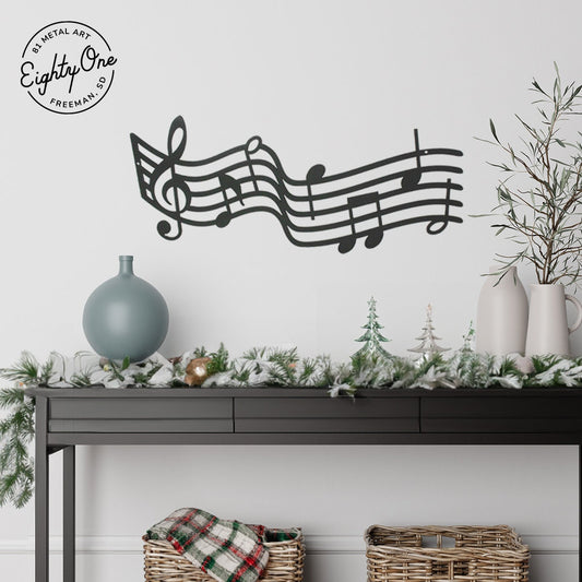 Black powder coat metal music staff wall sign above a console table