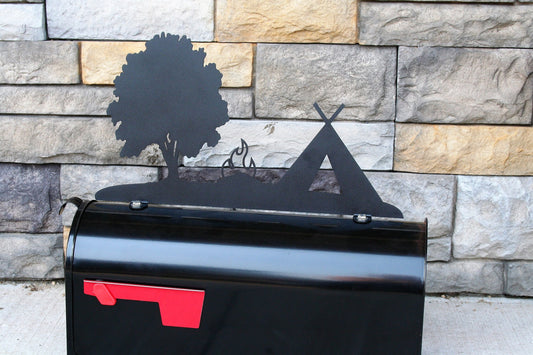 Black tent, tree, and campfire mailbox topper installed on a mailbox