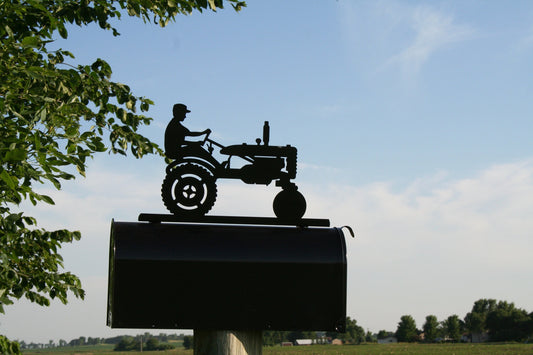 Black vintage tractor and driver mailbox topper installed on a mailbox