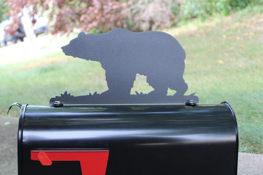 Black metal bear mailbox topper installed on a mailbox.